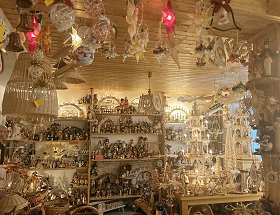 Blick in das Innere unseres Geschäftes, wo unterschiedliche hölzerne Pyramiden, Räuchermännchen und Nussknacker zu sehen sind. Sie sind mit warmen gelblichem Licht ausgeleuchtet.