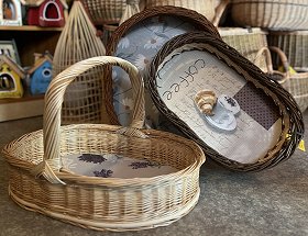 Es sind drei verschiedene Tabletts mit Motiv-Holzböden dargestellt. Das linke Tablett ist aus heller Weide geflochten und hat oben einen stabilen Tragegriff. Die anderen beiden Tabletts sind aus dunkler weide geflochten. Eines hat eine runde, das andere eine ovale Form.