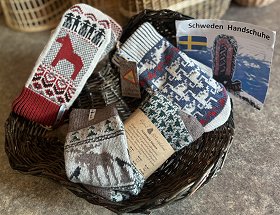 In einem dunkelbraunen Weidenkörbchen liegen verschiedene bunte schwedische Socken und Handschuhe mit skandinavischen Motiven.