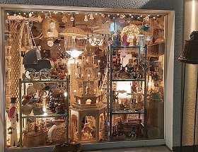 Das mittlere Schaufenster unseres Geschäftes mit einer beleuchteten, fünfstöckigen und hölzernen Pyramide sowie anderen erzgebirgischen Holzkunstartikeln in weihnachtlicher Beleuchtung